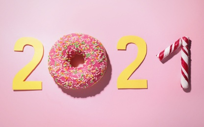 Number 2021 made with donut and candies on pink background, flat lay