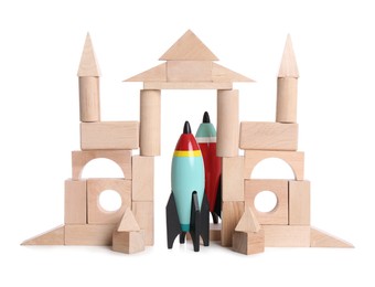 Photo of Castle made of wooden building blocks and bright toy rockets on white background
