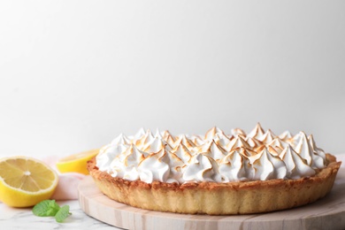 Photo of Serving board with delicious lemon meringue pie on white marble table