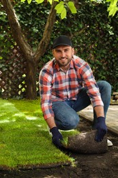 Photo of Young man laying grass sod on ground at backyard