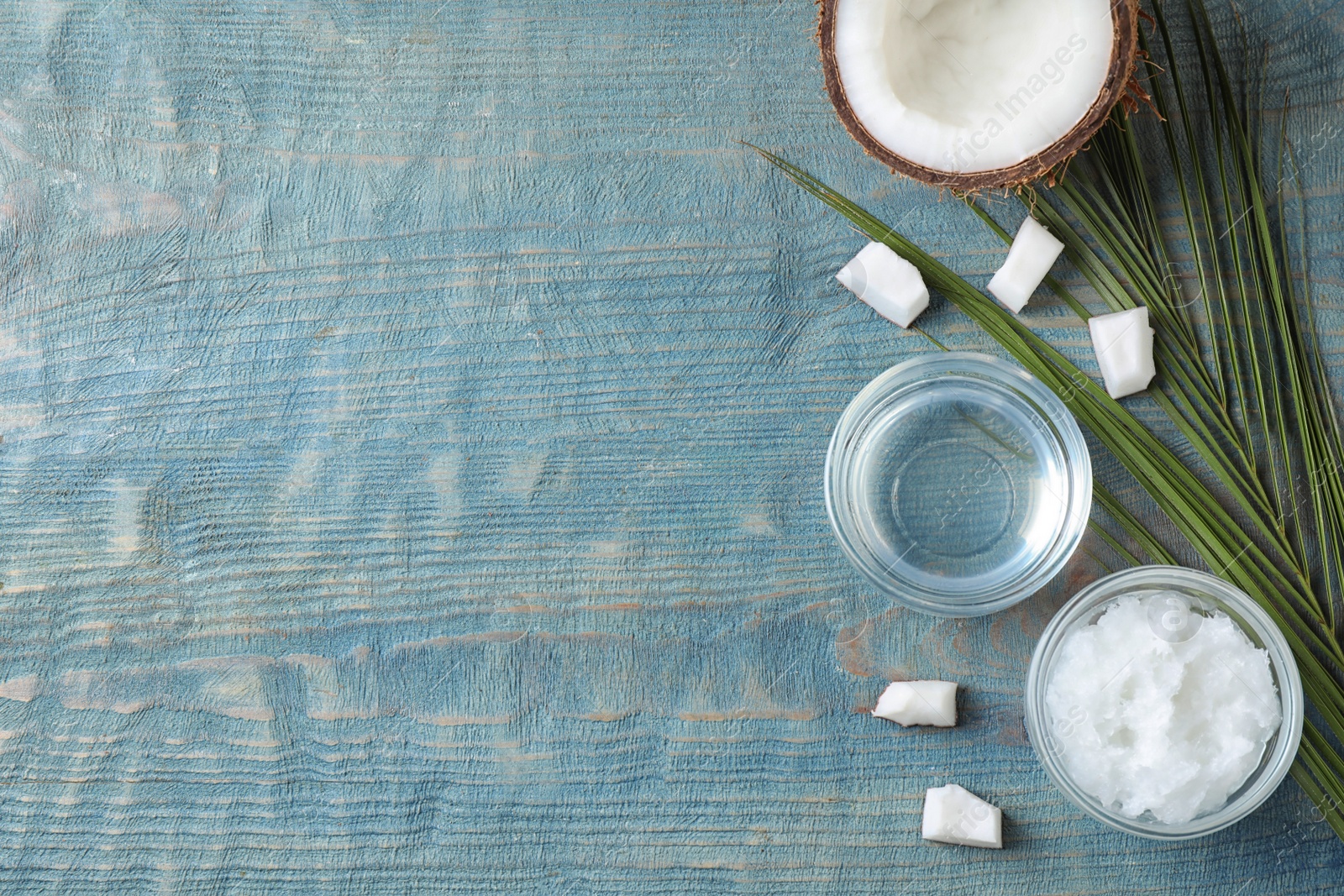 Photo of Flat lay composition with coconut oil on light blue wooden table, space for text