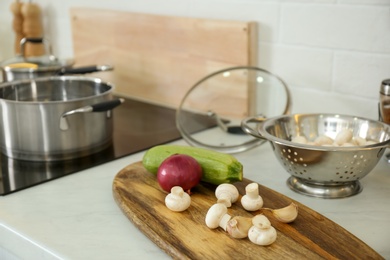 Photo of Fresh vegetables and mushrooms on white countertop in modern kitchen