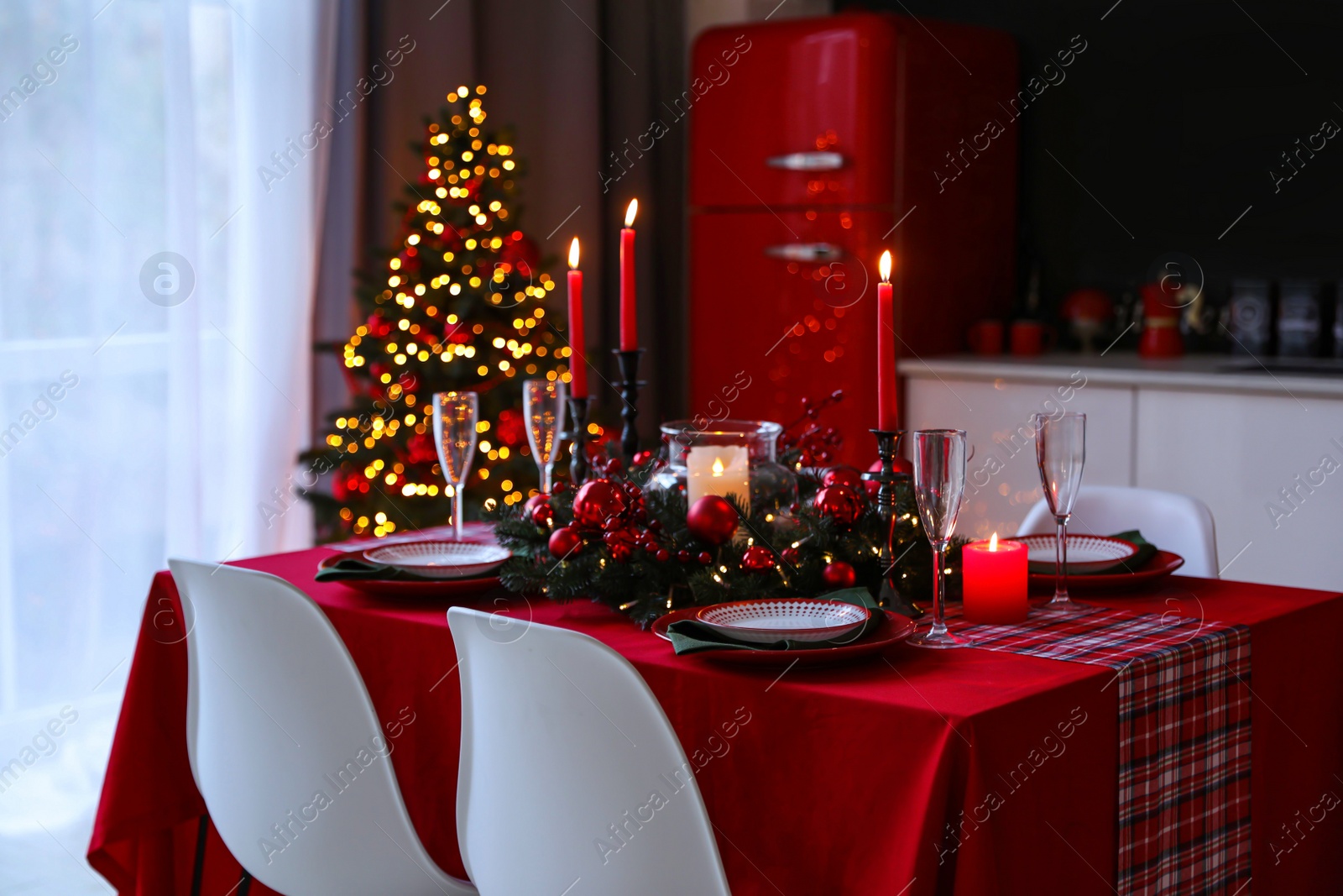 Photo of Table served for festive dinner and Christmas tree in stylish kitchen interior