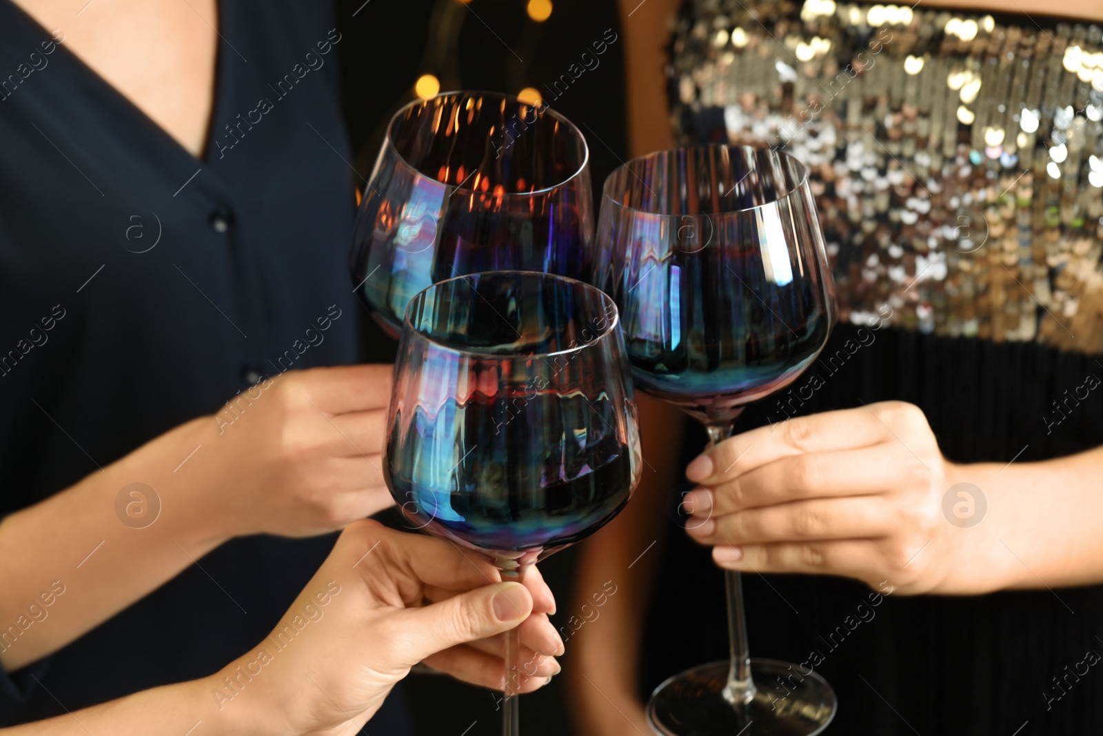 Photo of Women clinking glasses of red wine at party, closeup