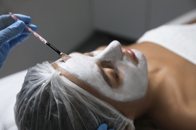 Cosmetologist applying mask on client's face in spa salon