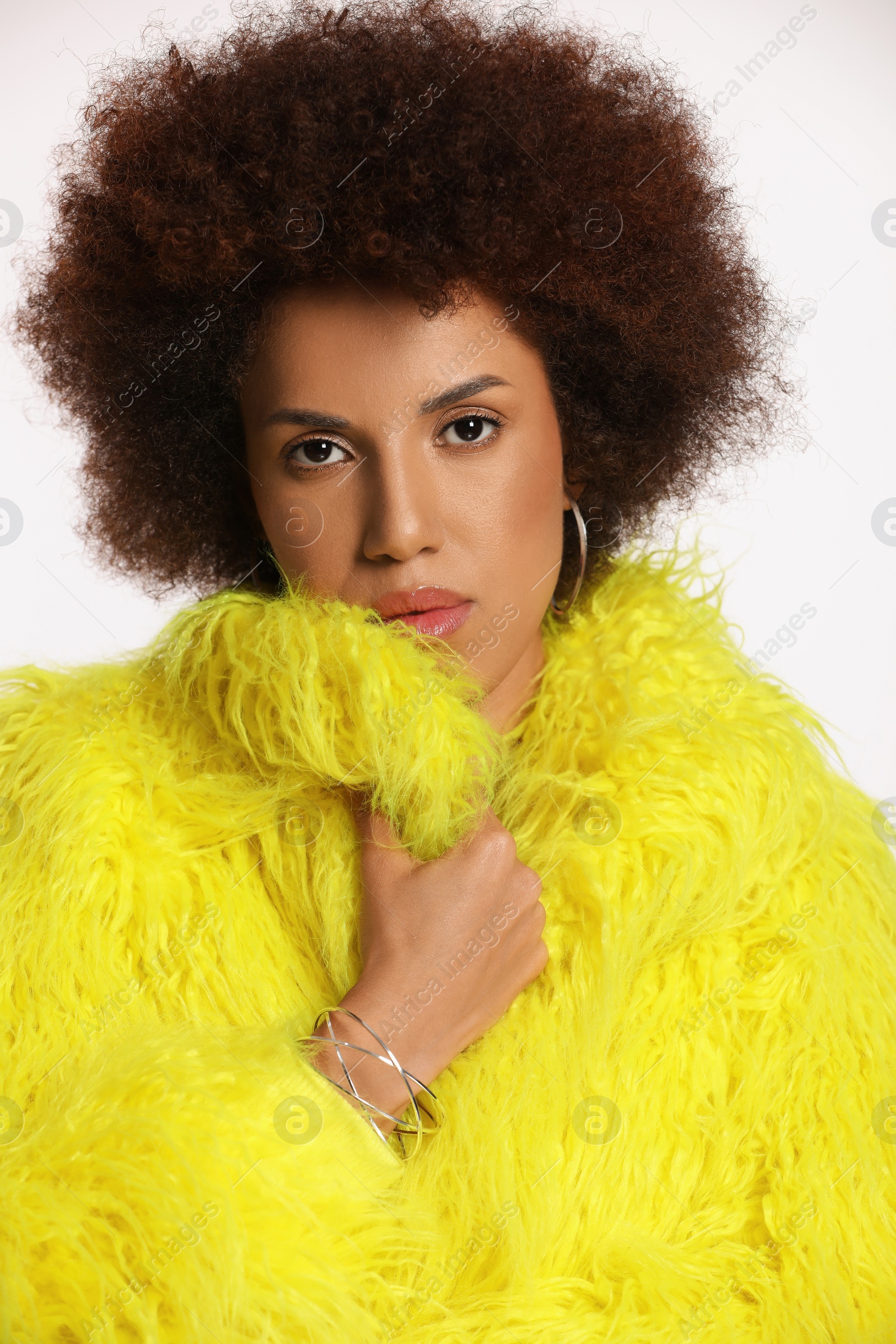 Photo of Portrait of beautiful young woman in stylish yellow fur coat on white background