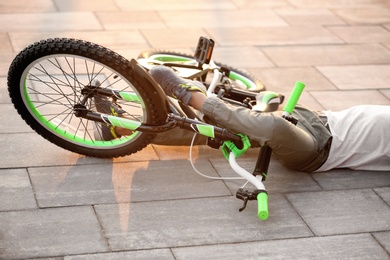 Photo of Little boy fallen off his bicycle on street, closeup