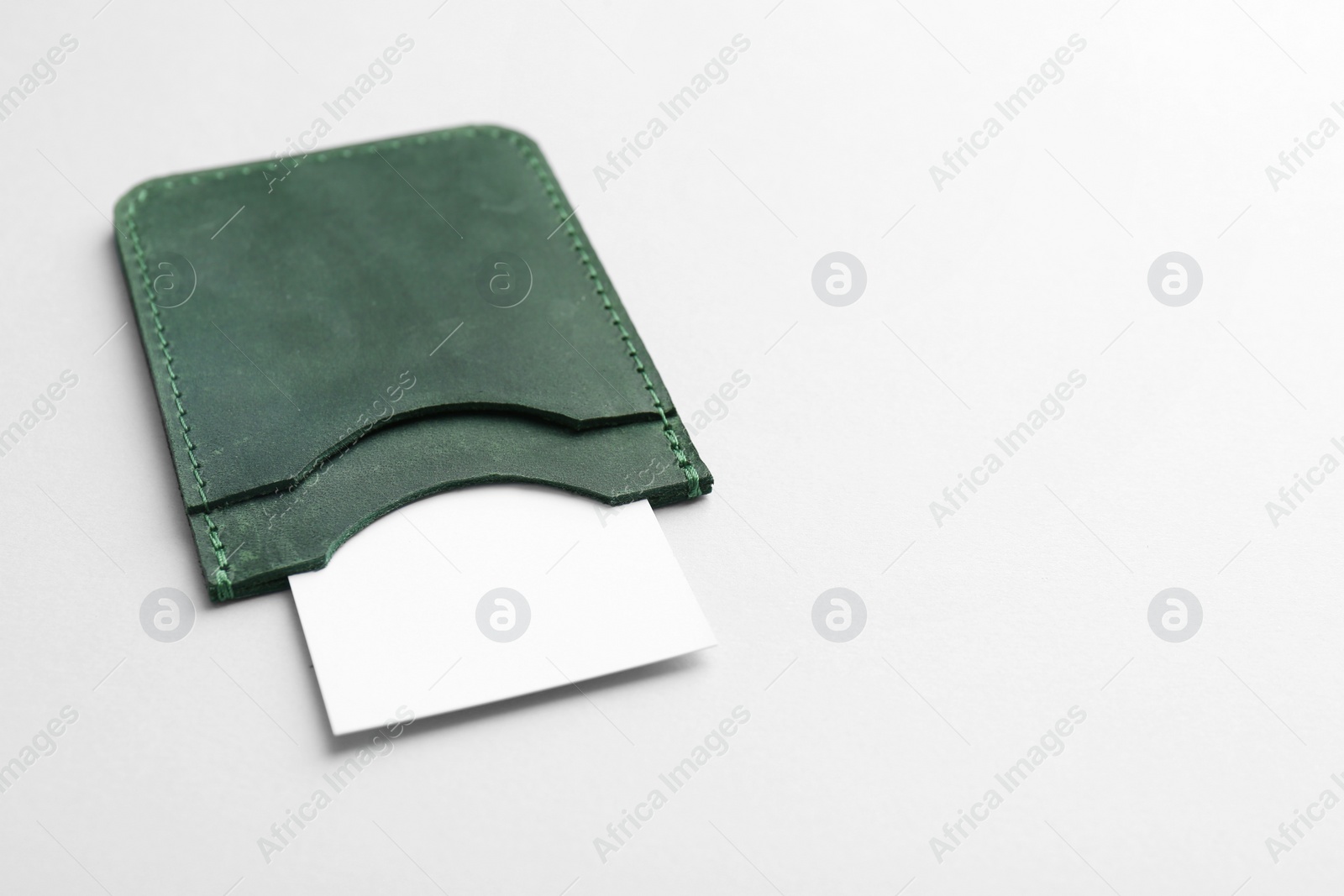Photo of Leather business card holder with blank card on light grey background. Space for text
