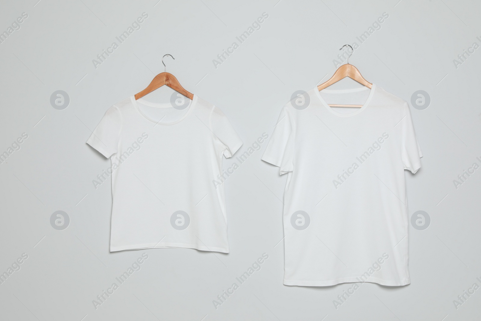 Photo of Hangers with blank t-shirts on gray background. Mock up for design