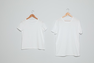 Photo of Hangers with blank t-shirts on gray background. Mock up for design