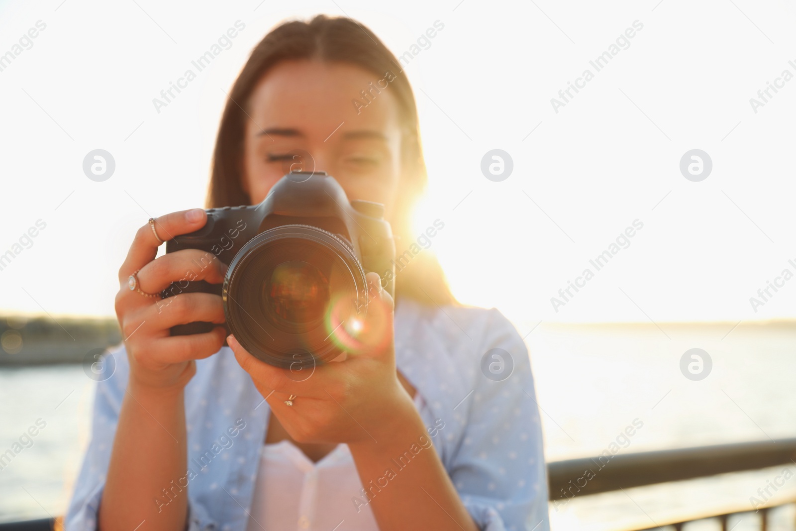 Photo of Young photographer taking picture with professional camera outdoors