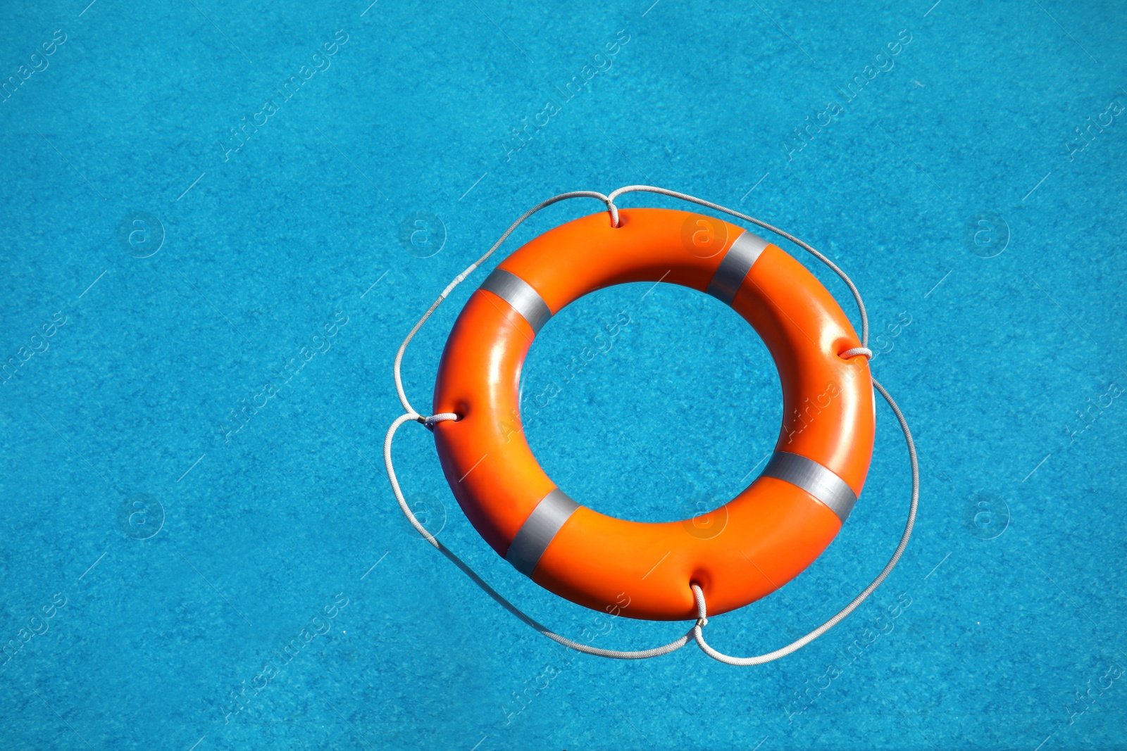 Photo of Bright orange inflatable ring floating in swimming pool, top view