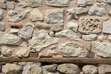 Photo of Texture of old stone wall with wooden plank as background, closeup