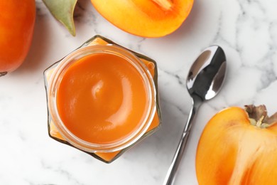 Delicious persimmon jam and fresh fruits on white marble table, flat lay