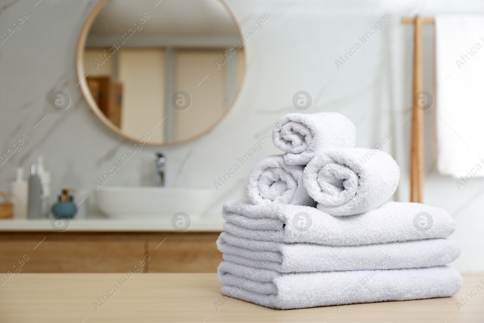 Photo of White towels on wooden table in bathroom. Space for text