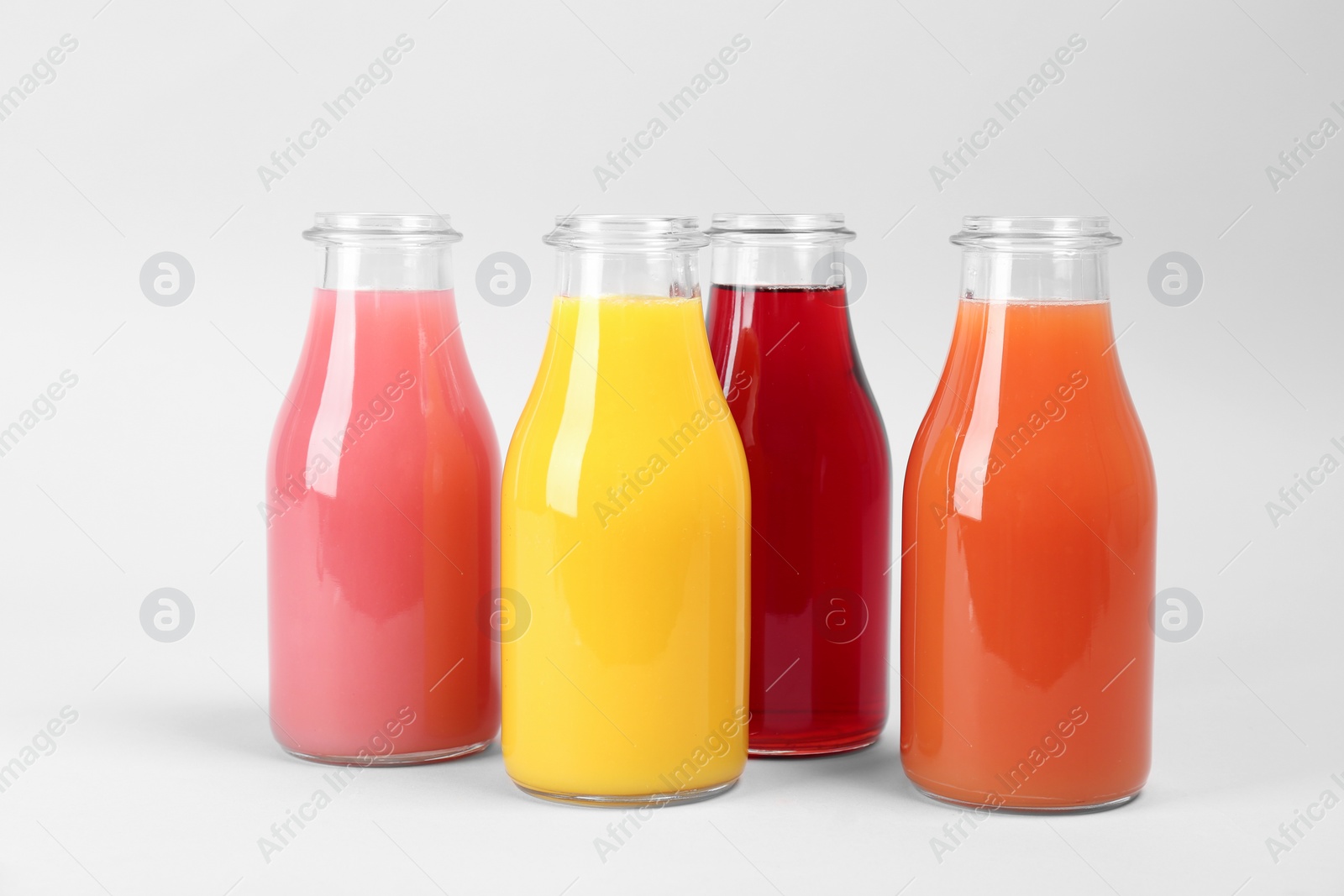 Photo of Bottles with delicious colorful juices on light background