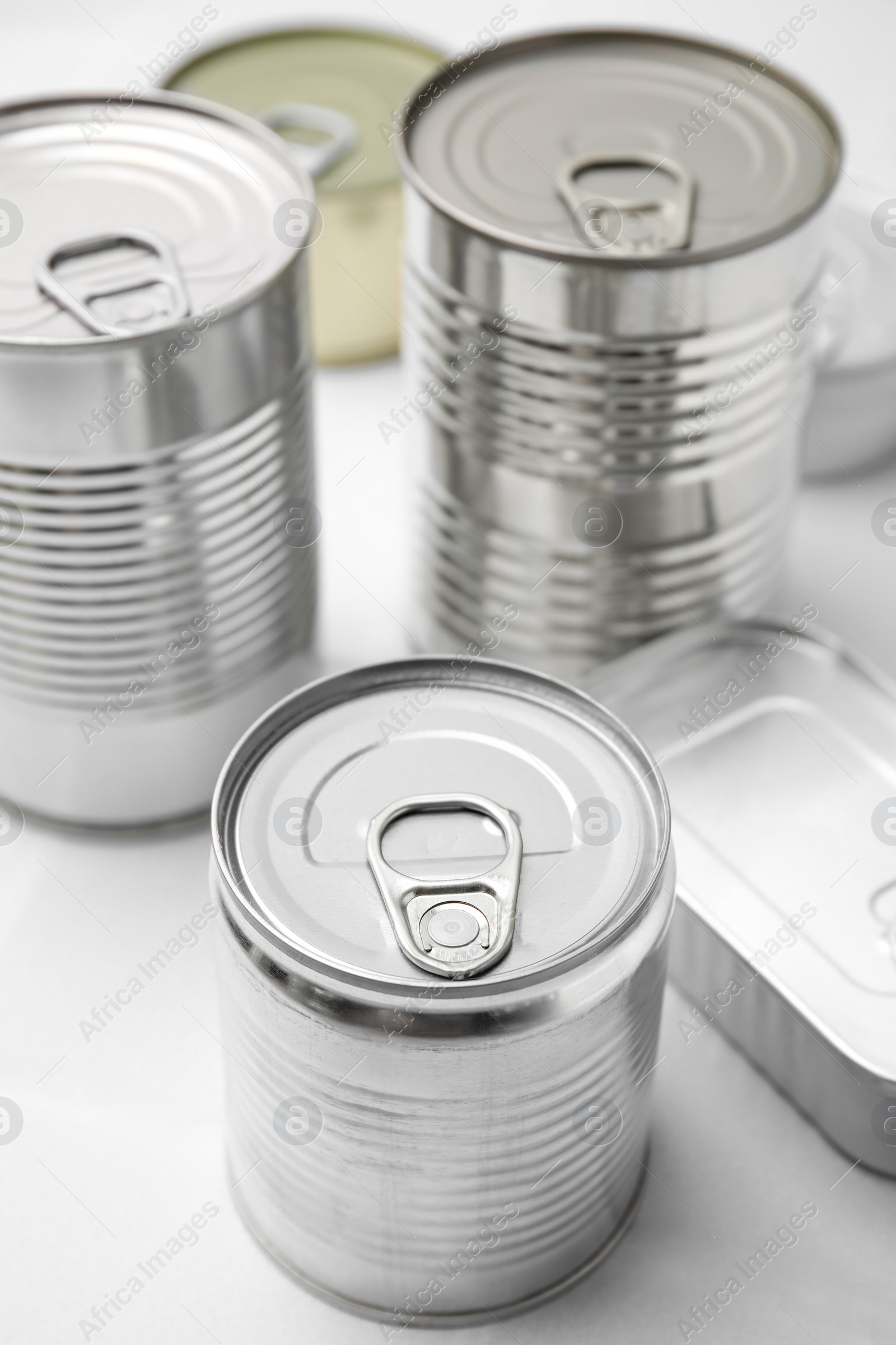 Photo of Many closed tin cans on white tiled table, closeup