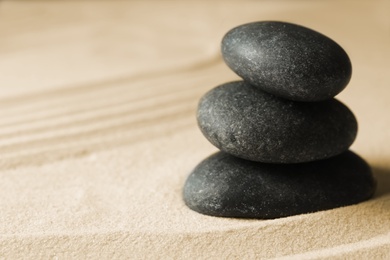 Photo of Stacked zen garden stones on sand with pattern, space for text. Meditation and harmony