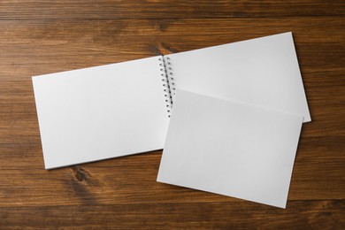 Sheet of paper and blank brochure on wooden table, flat lay. Mockup for design