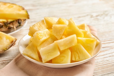 Photo of Plate with fresh pineapple slices on wooden background, closeup