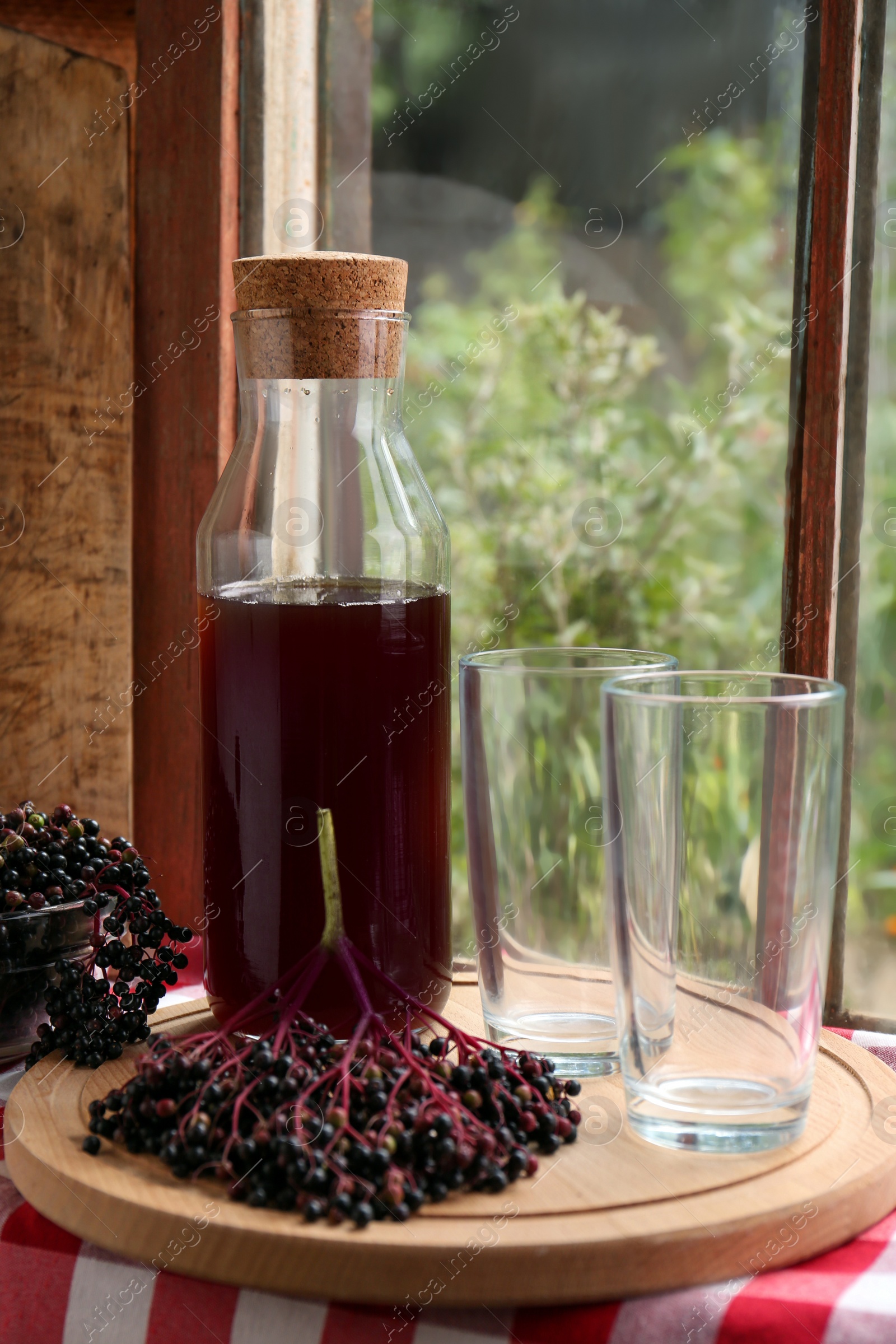 Photo of Elderberry drink and Sambucus berries on table near window