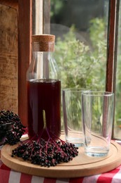 Elderberry drink and Sambucus berries on table near window