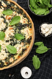 Delicious homemade spinach quiche and ingredients on table, flat lay