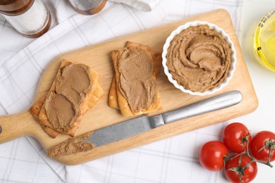 Photo of Crispy crackers with delicious meat pate served on white table, flat lay
