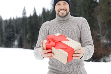 Photo of Happy man with gift box outdoors. Winter vacation