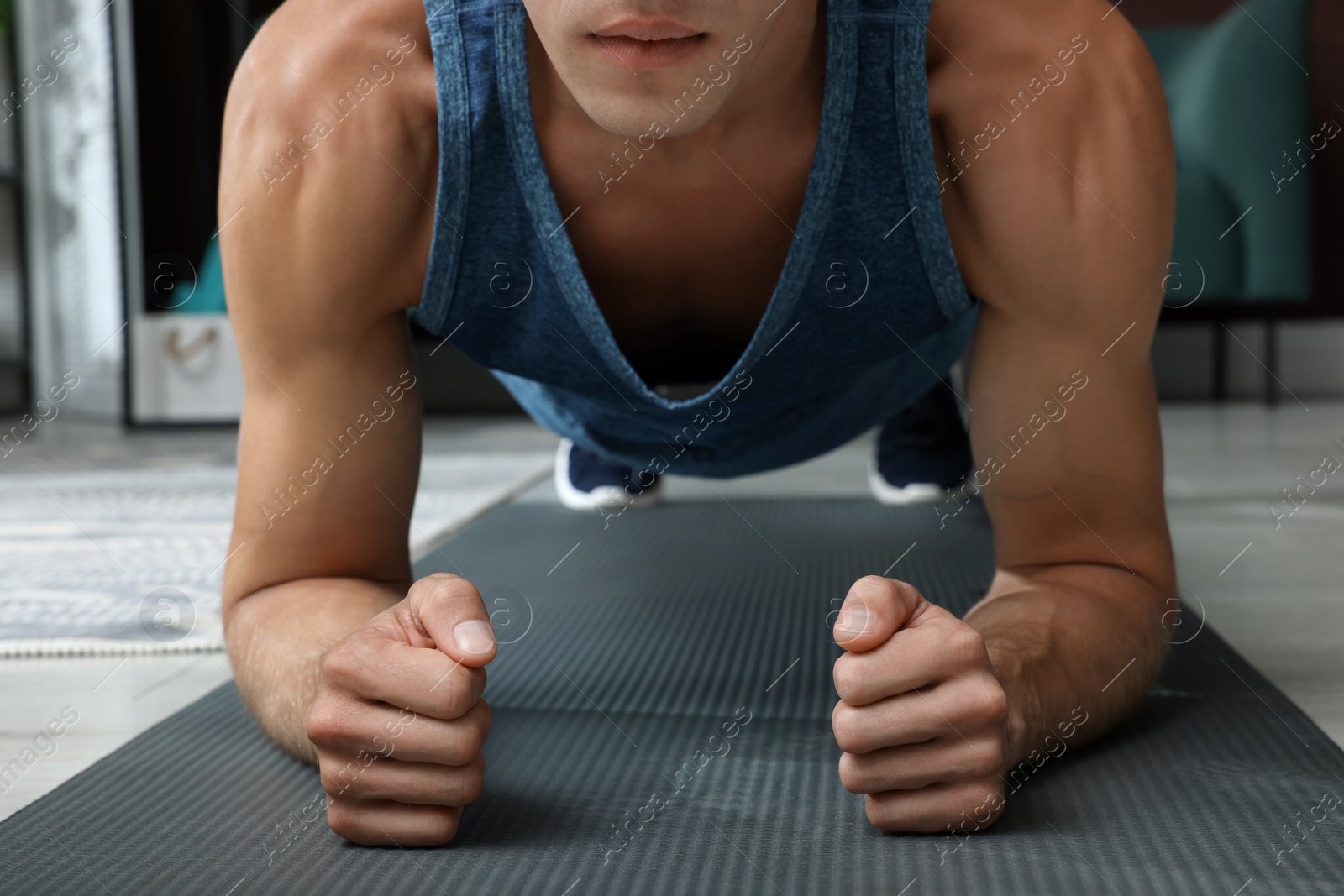 Photo of Man doing plank exercise on floor at home, closeup