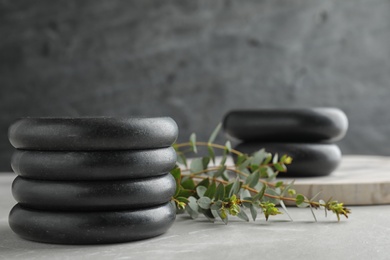 Photo of Stack of spa stones and green leaves on grey table, space for text