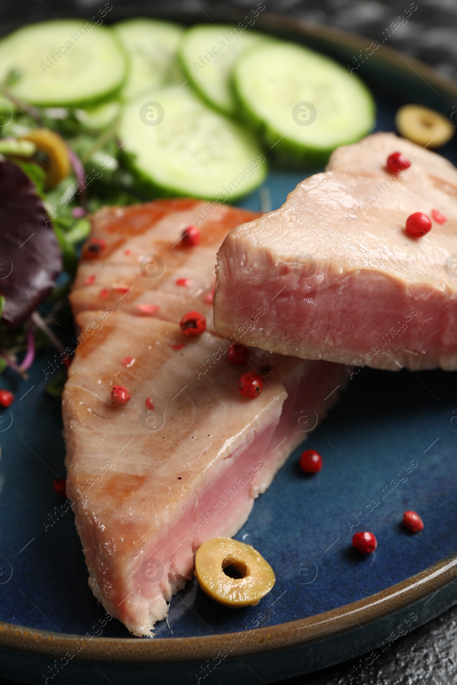 Photo of Pieces of delicious tuna with olive and spices on plate, closeup