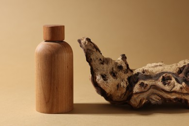 Photo of Wooden bottlecosmetic product and tree bark on dark beige background