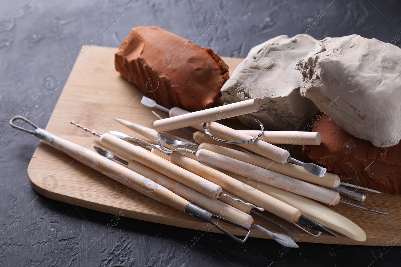 Photo of Clay and set of modeling tools on black table