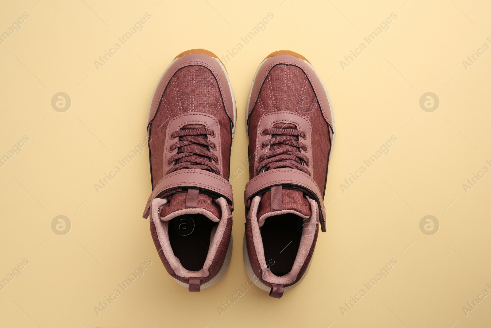 Photo of Pair of stylish kid's sneakers on beige background, top view