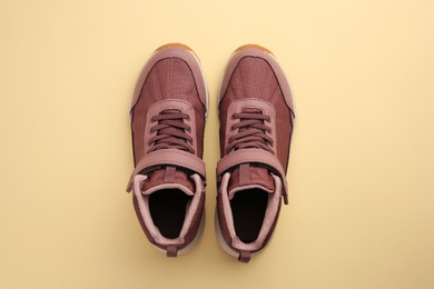 Photo of Pair of stylish kid's sneakers on beige background, top view