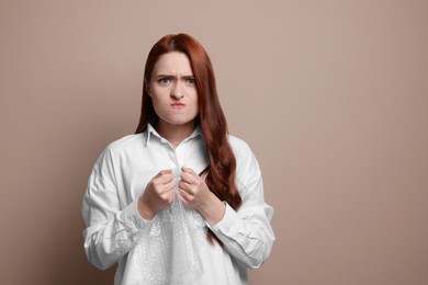 Angry woman popping bubble wrap on beige background. Stress relief