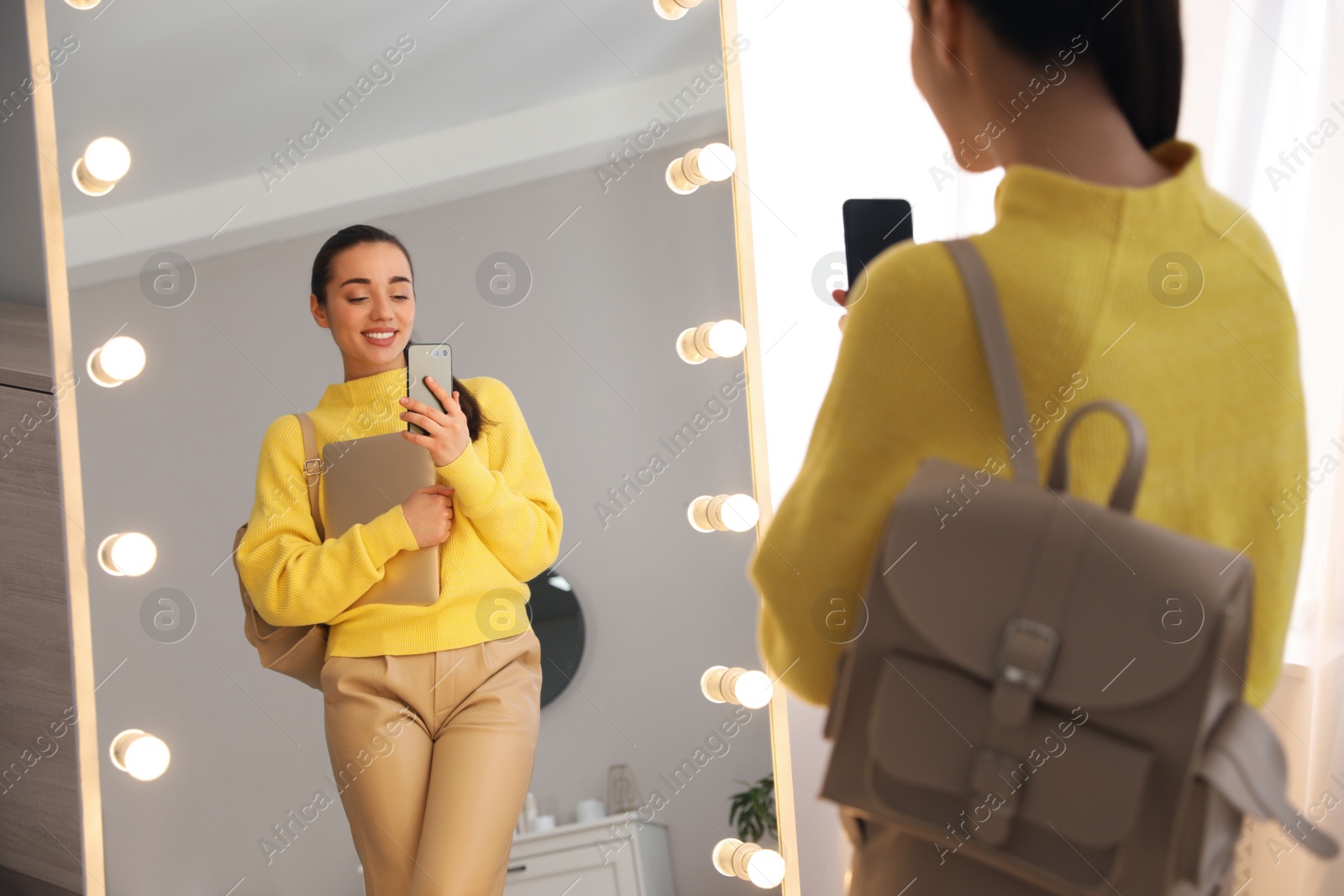 Photo of Young woman taking mirror selfie in stylish outfit at home. Morning routine