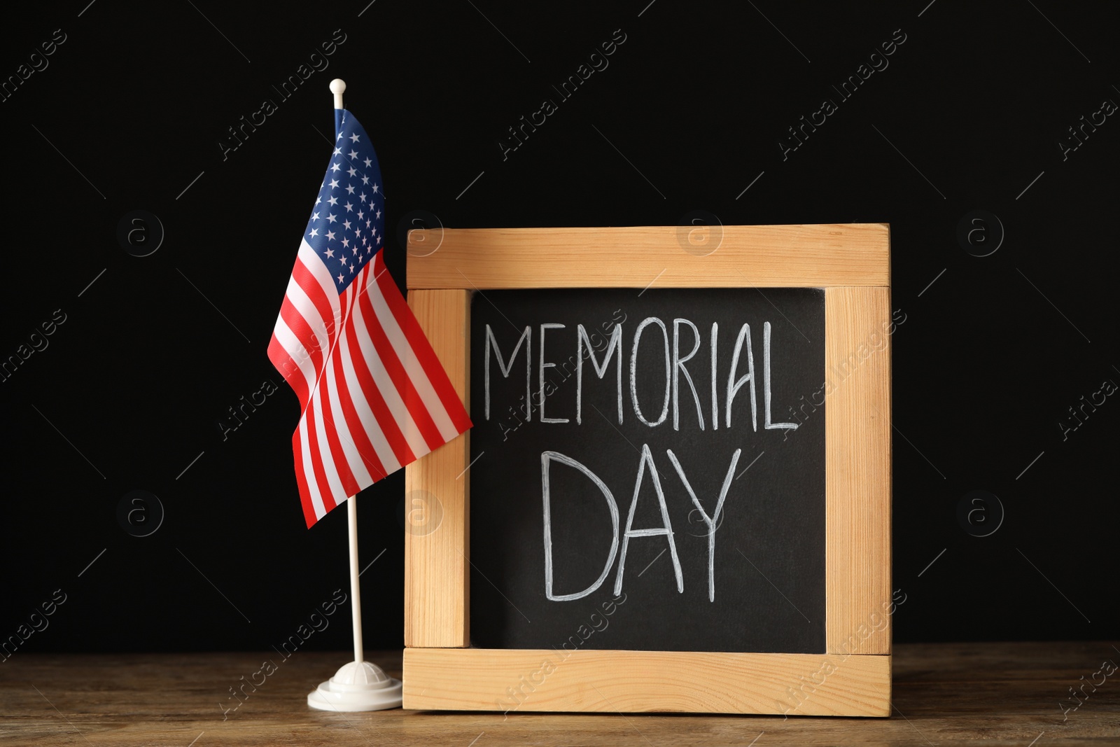 Photo of Blackboard with phrase Memorial Day and American flag on wooden table