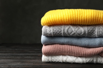 Photo of Stack of folded knitted sweaters on table. Space for text