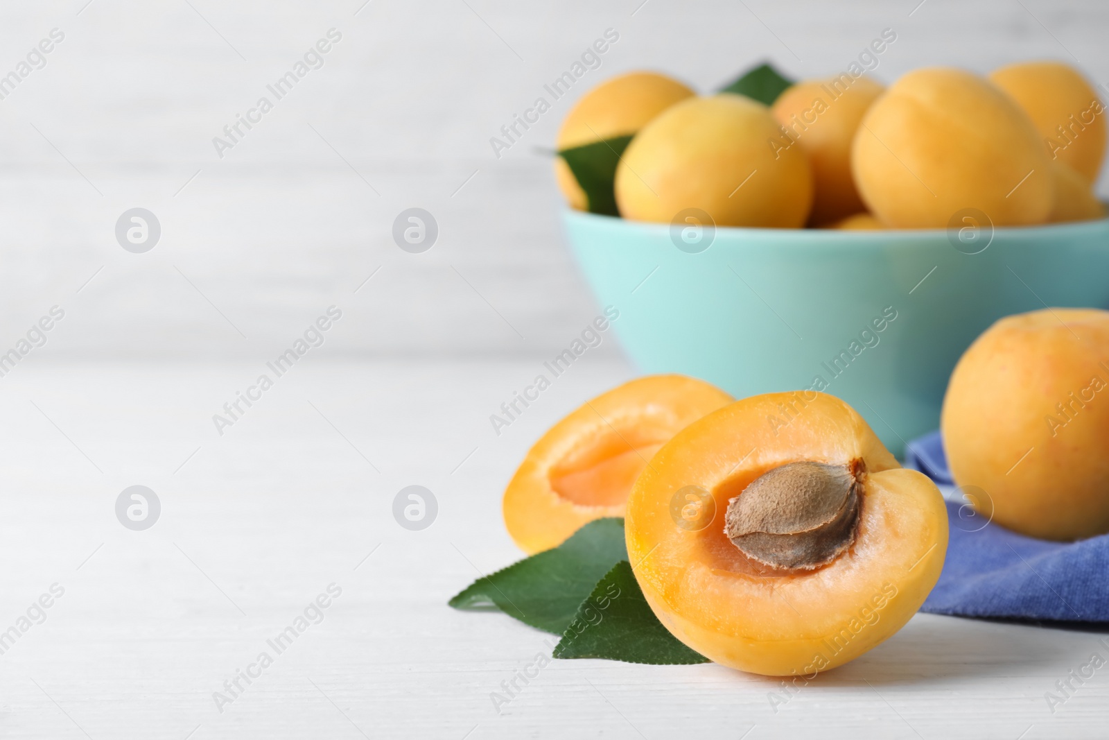 Photo of Delicious fresh ripe apricots on white wooden background. Space for text