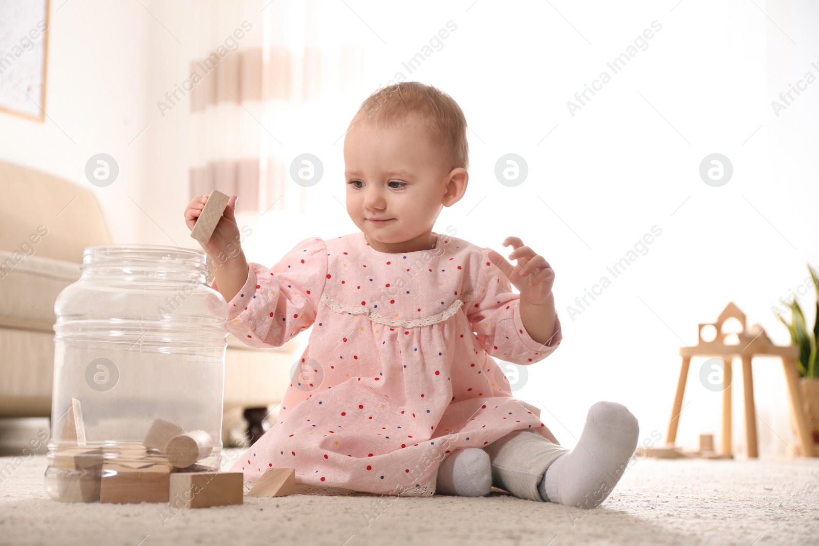 Photo of Cute child playing with wooden building blocks on floor at home