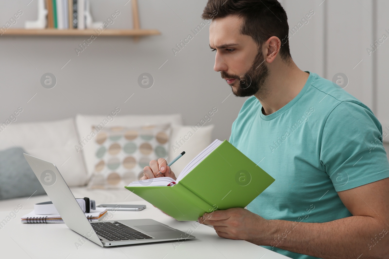 Photo of Online test. Man studying with laptop at home