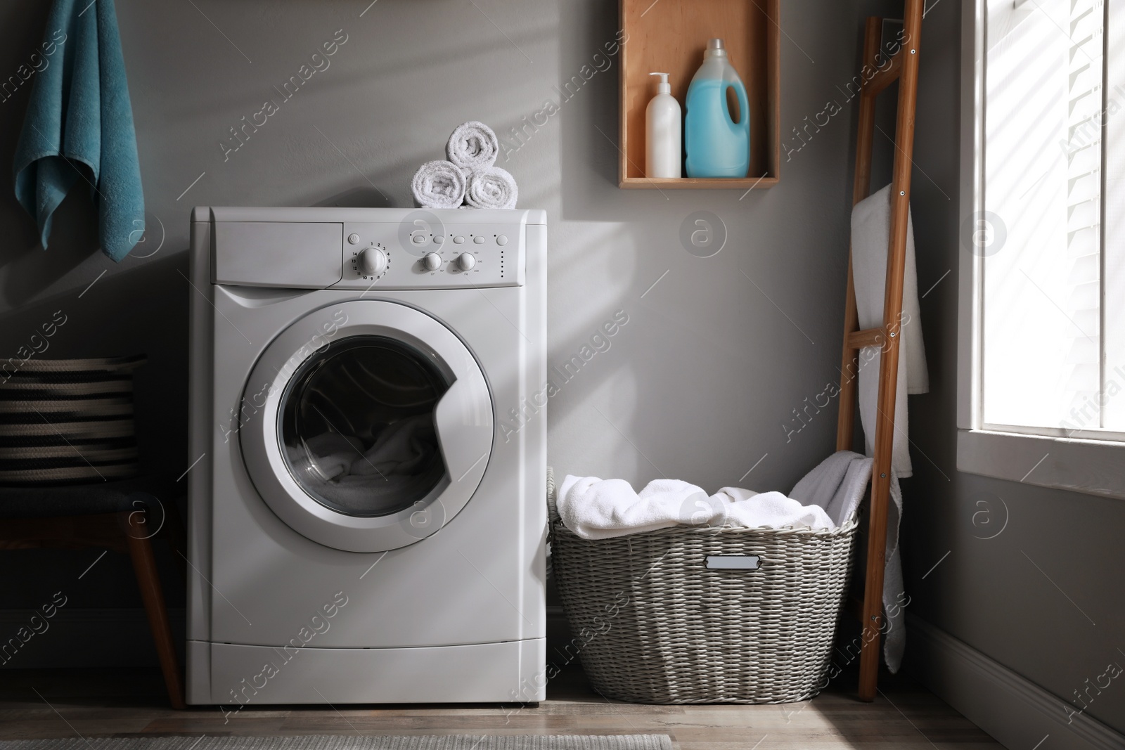 Photo of Laundry room interior with modern washing machine near light wall