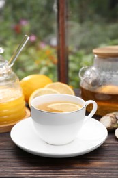 Cup of delicious tea with lemon and honey on wooden table