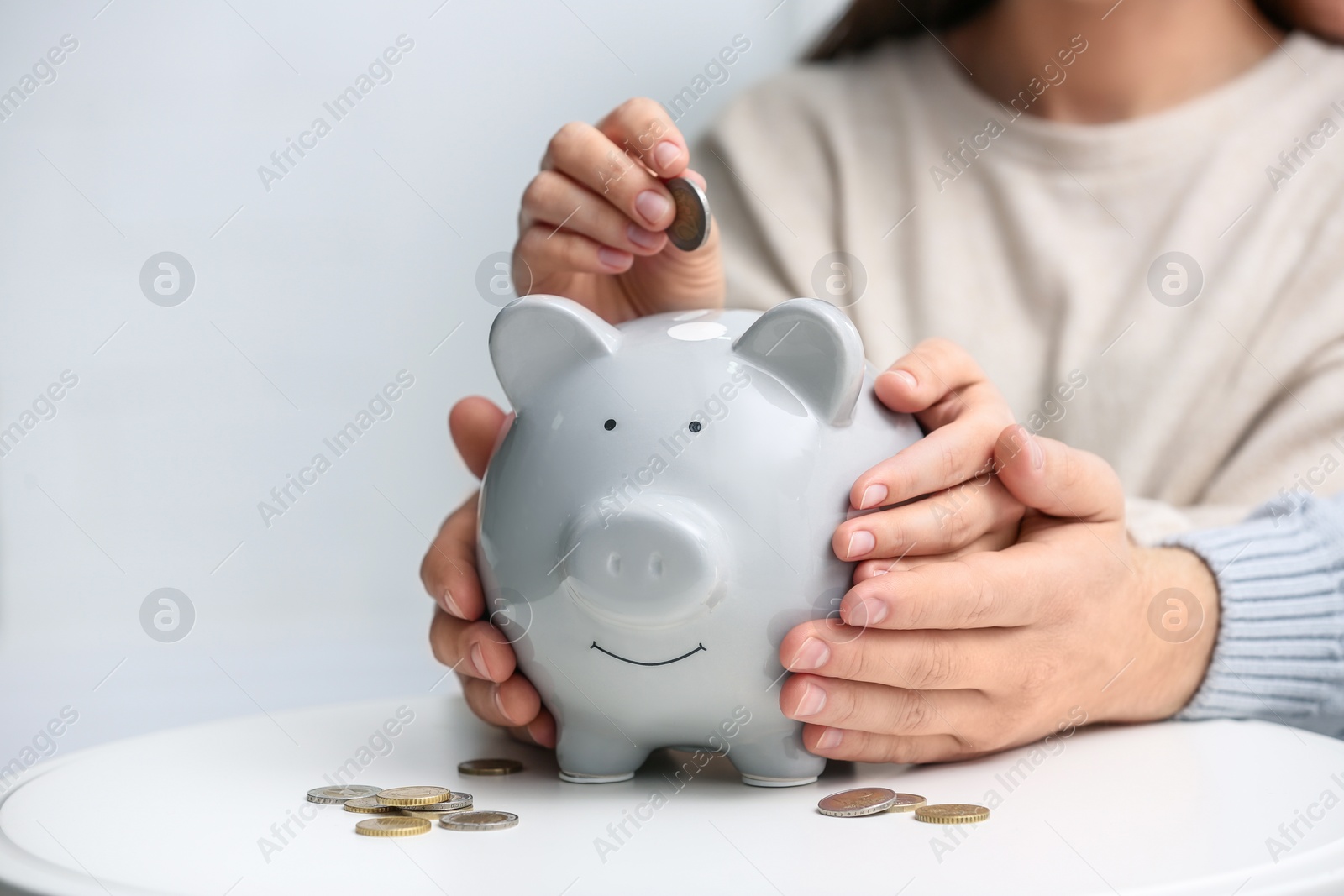 Photo of Couple with piggy bank at white table, closeup