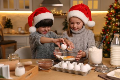 Photo of Cute little children making dough for Christmas cookies in kitchen