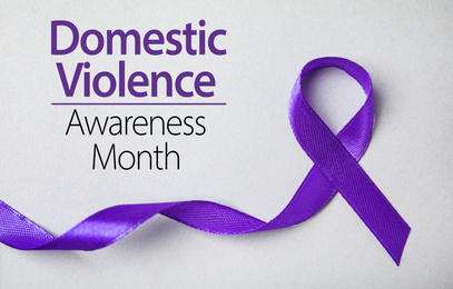 Image of Purple ribbon on grey background, top view. Symbol of Domestic Violence Awareness