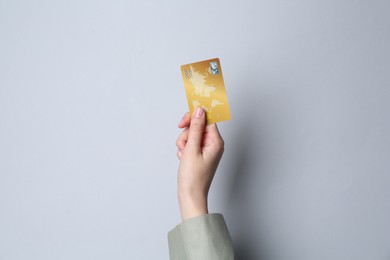 Photo of Woman holding credit card on light grey background, closeup