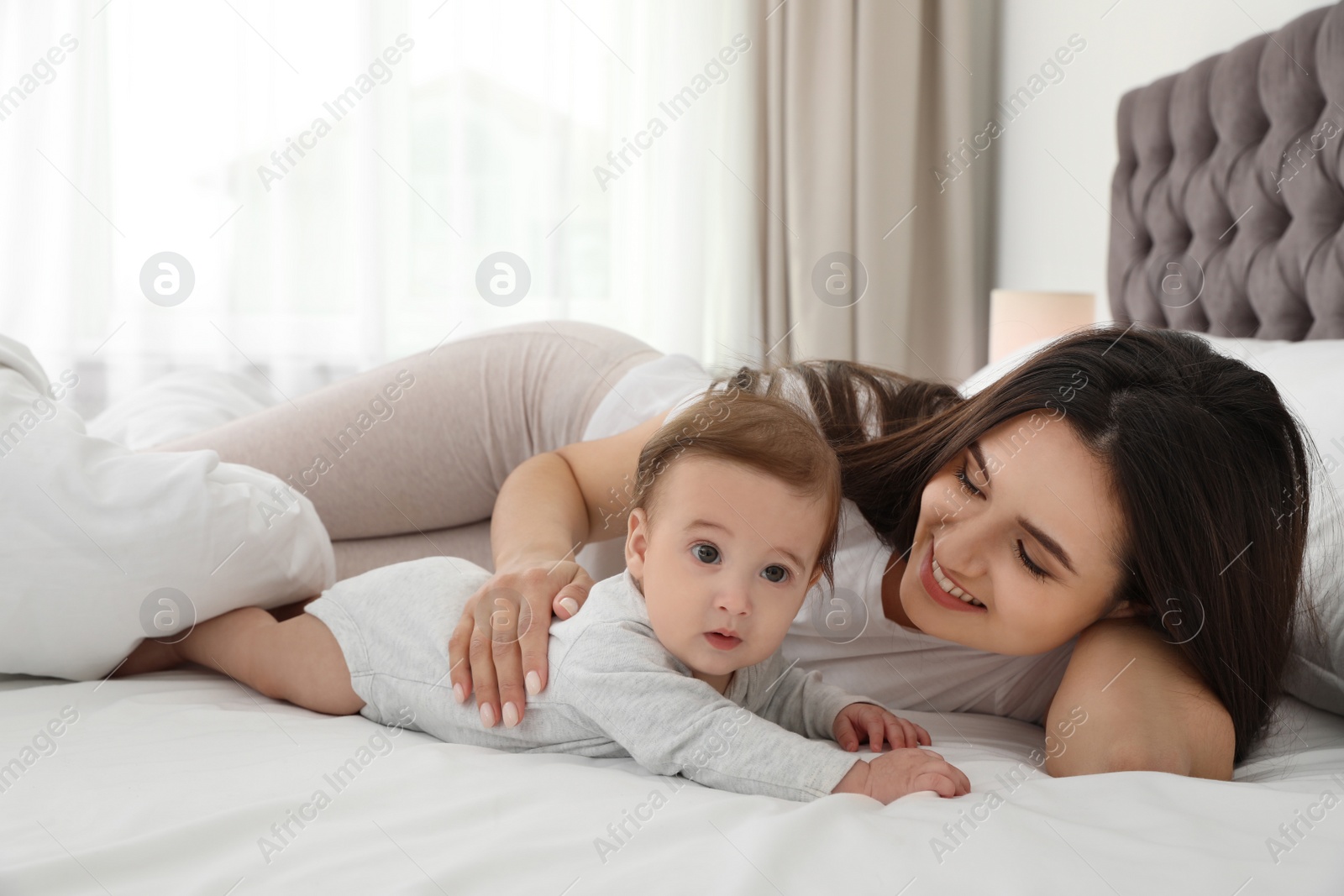 Photo of Portrait of mother with her cute baby lying on bed indoors